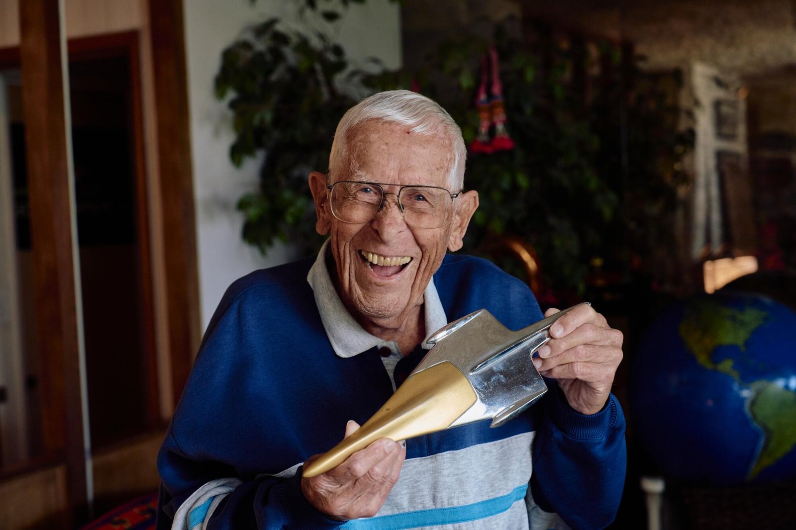 A man holding a metallic, spaceship-like hood ornament. 