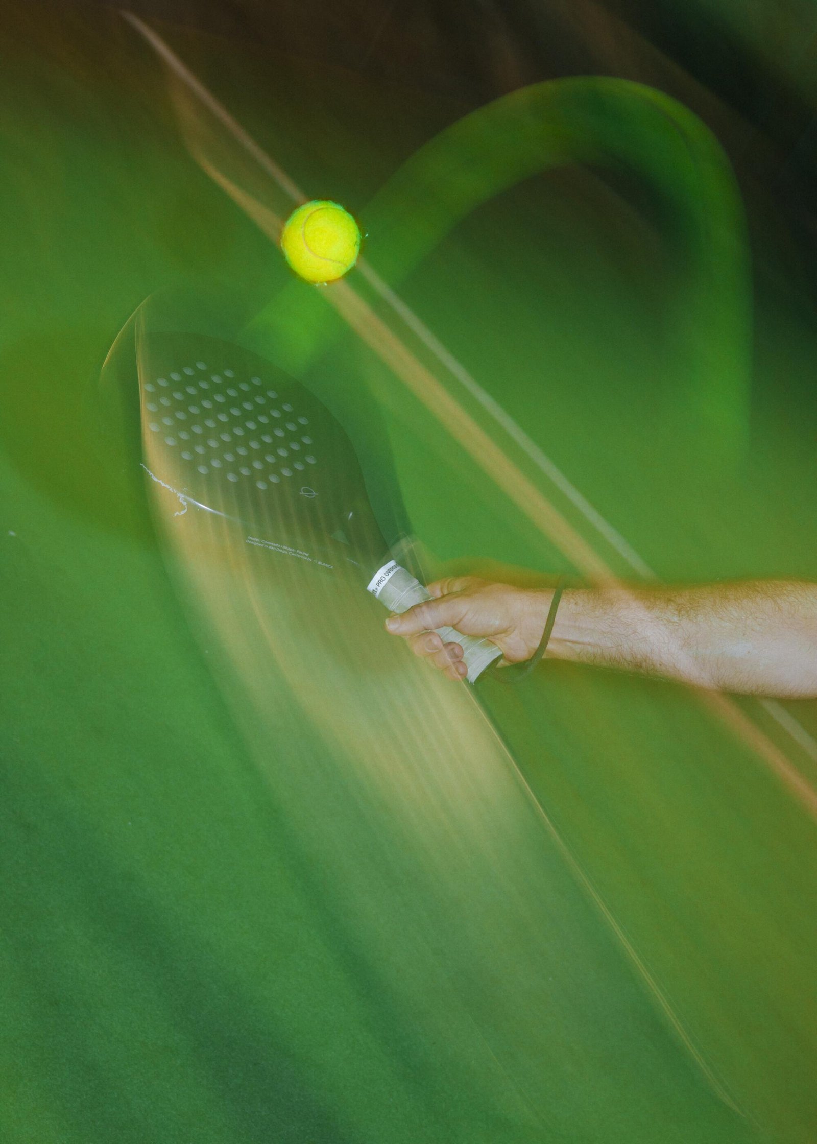 A blurred shot of a padel swing and ball.
