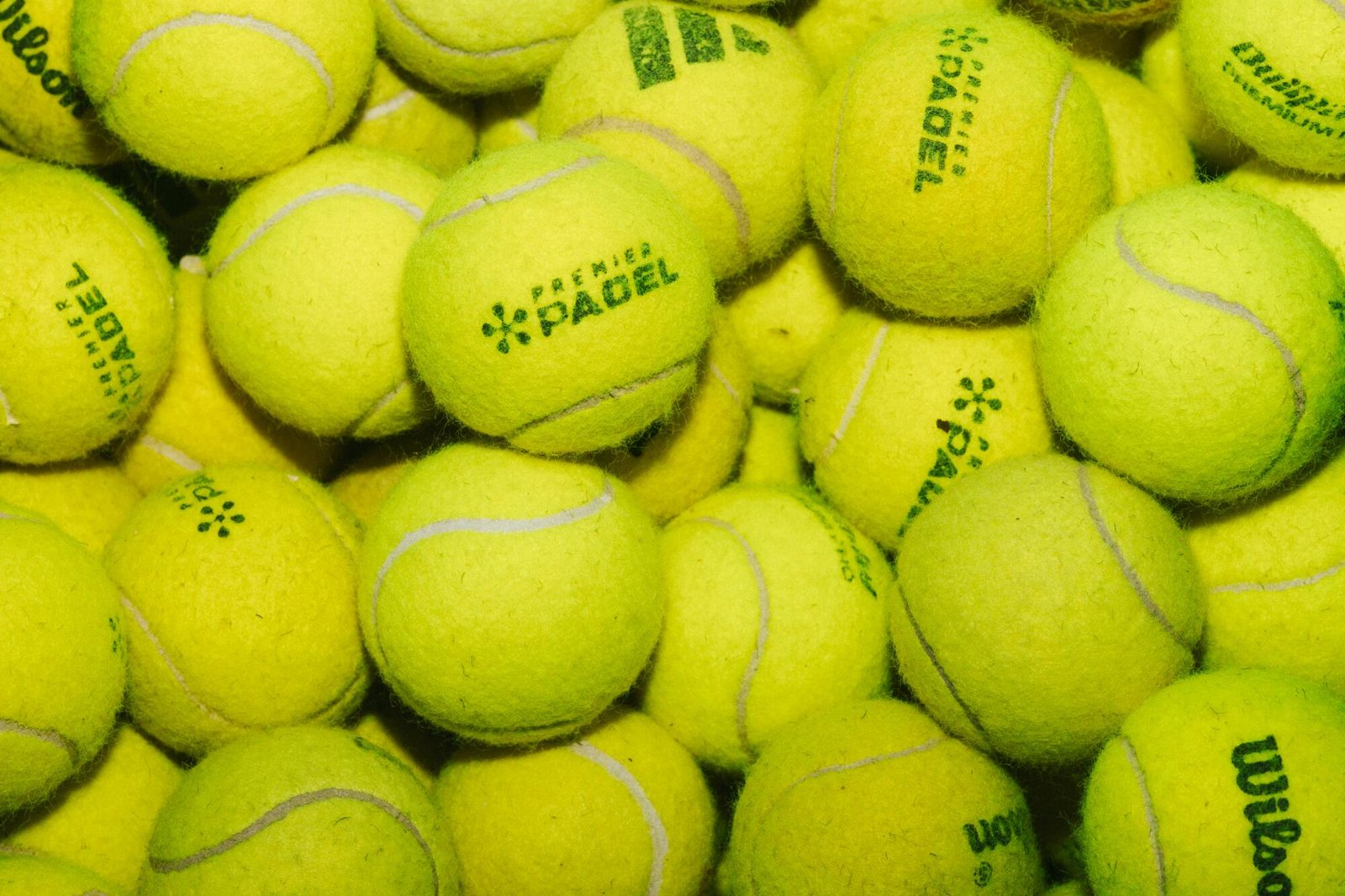 Fuzzy yellow padel balls fill the frame.