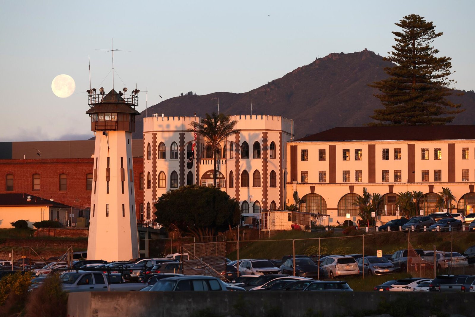 A view of the white concrete exterior of a prison complex with a watchtower