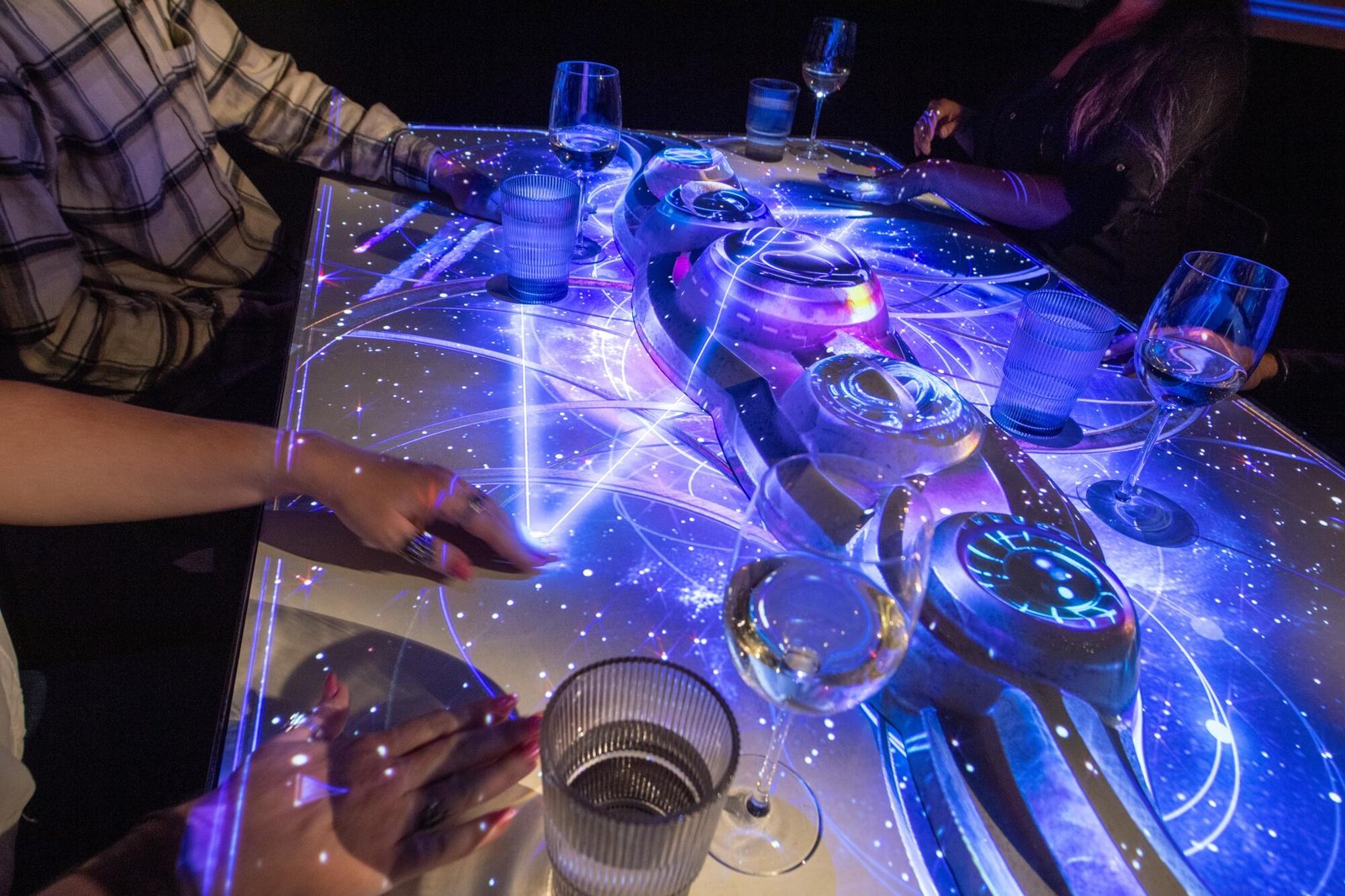 A table is illuminated around the hands of guests.