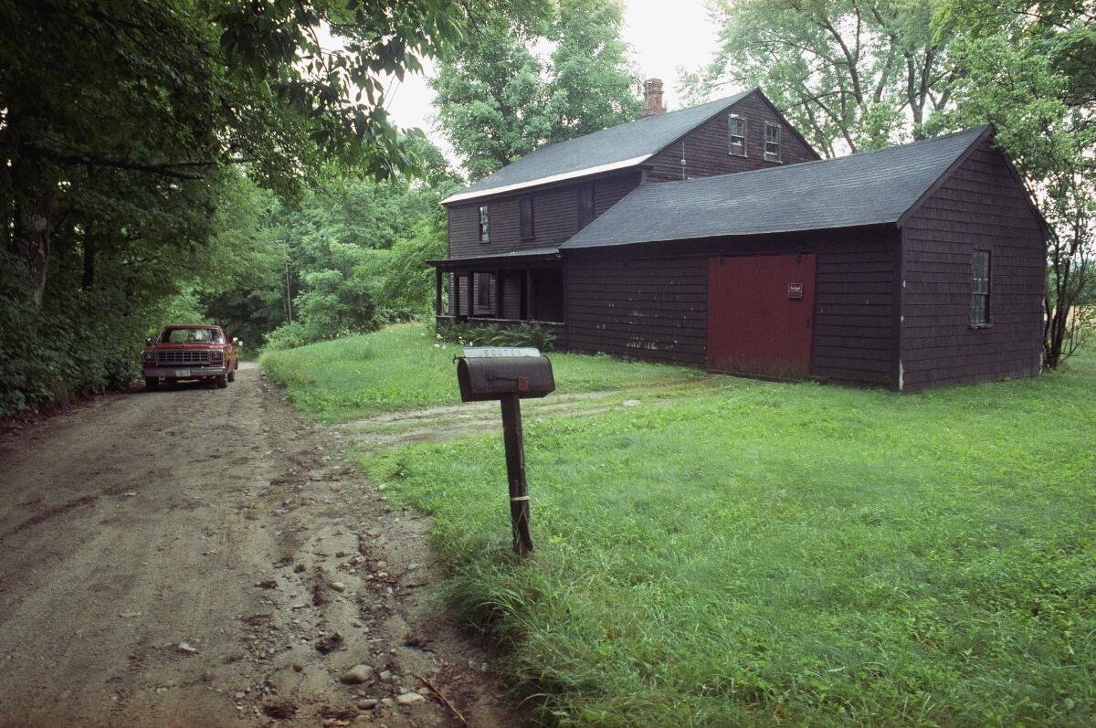 The home of David Souter along a dirt road amid trees and grass.