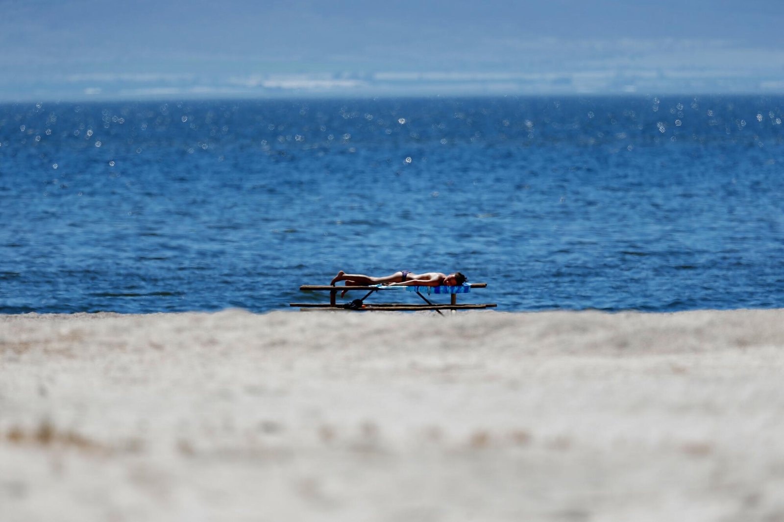 A lone sunbather lies in a reclining chair at the Salton Sea State Recreation Area.