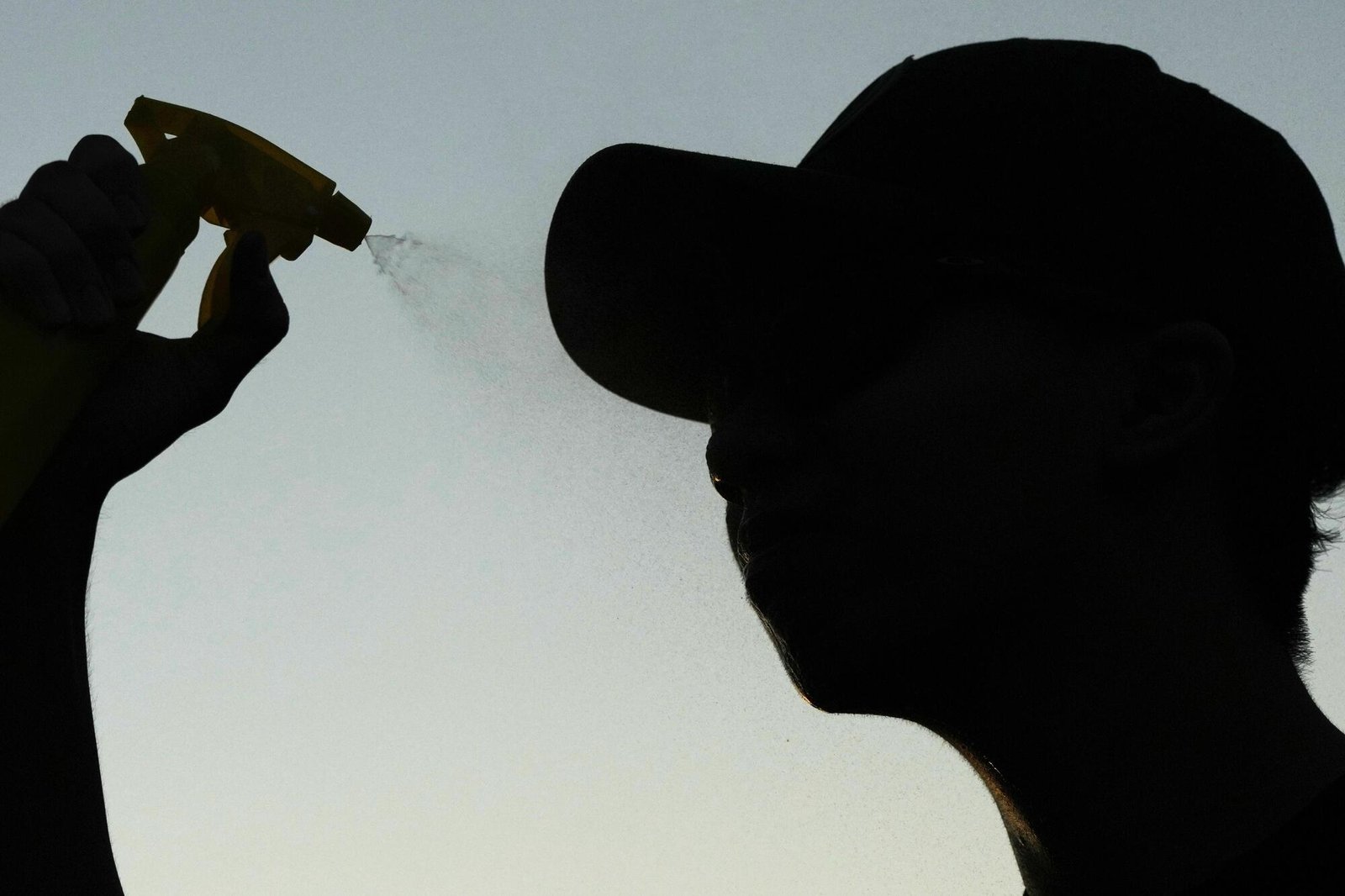 John Nguyen sprays water to cool off after shooting hoops during a hot weather day in Deerfield, Ill..