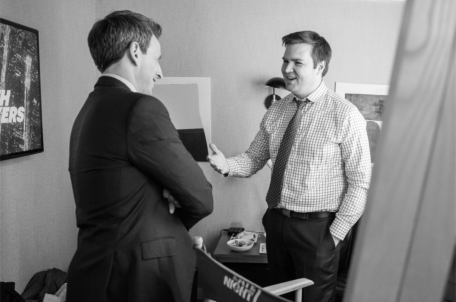black-and-white photo of Seth Meyers in suit talking with with smiling Vance in shirt and tie in show dressing room