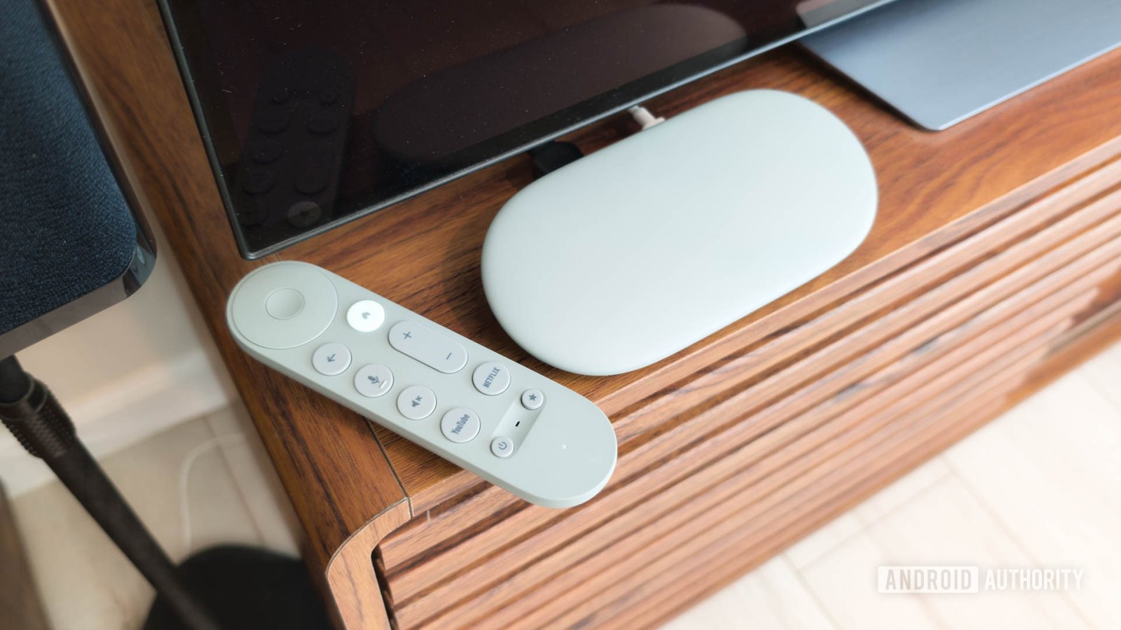 Google TV Streamer with remote on TV console hero Google TV Streamer with remote on TV console hero