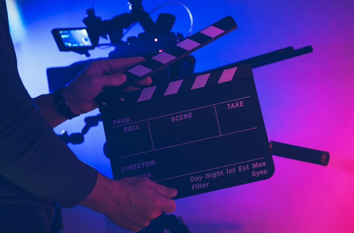Two hands hold up a clapperboard