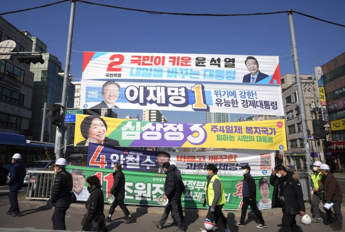 People walk past rows of banners on a street