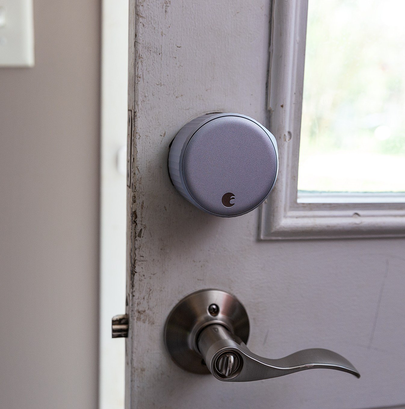 A large silver door lock on a door above a lever handle