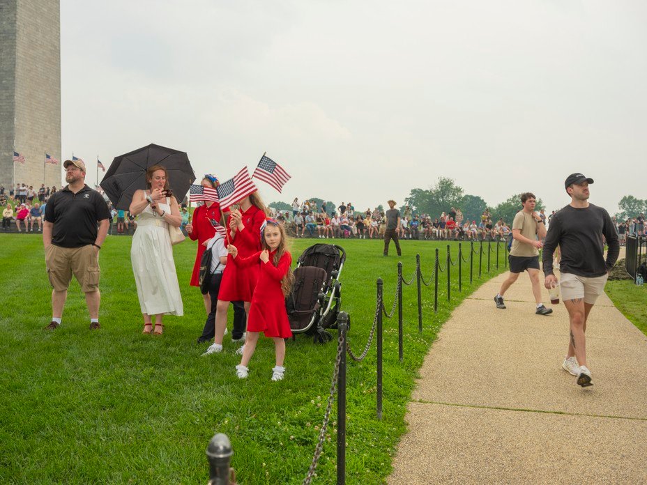 Picture of parade-goers waving flags beneath the Washington Monument.