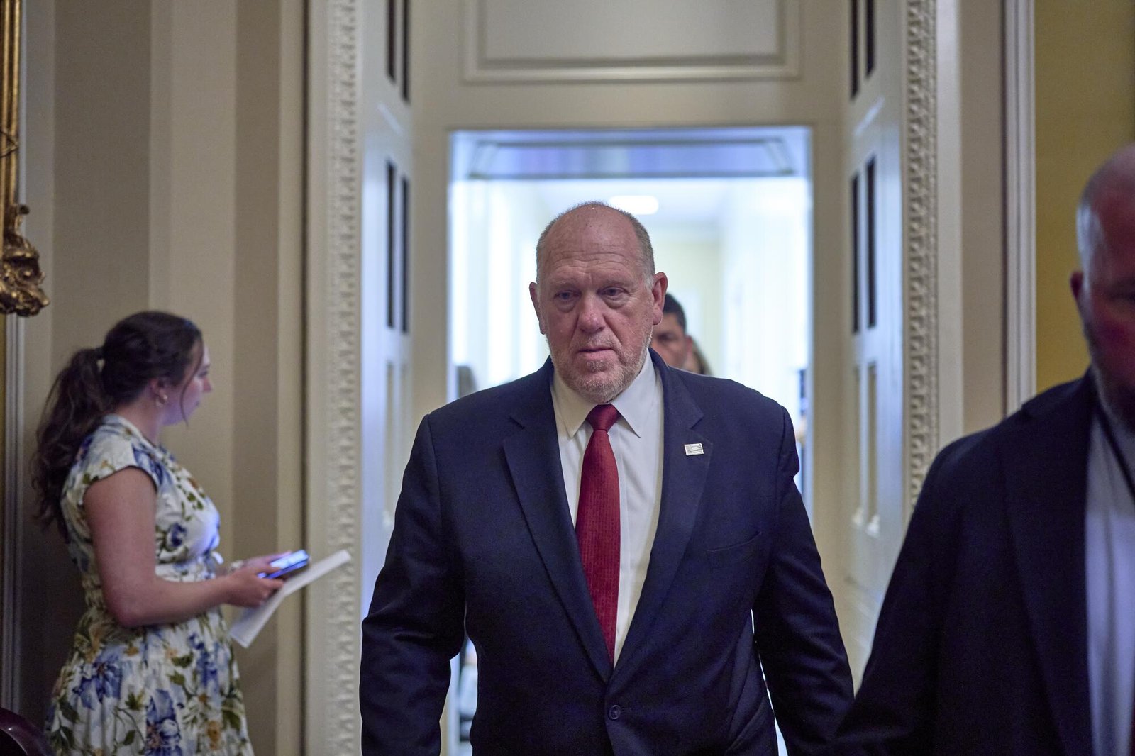 A man in a business suit walks through a hallway.