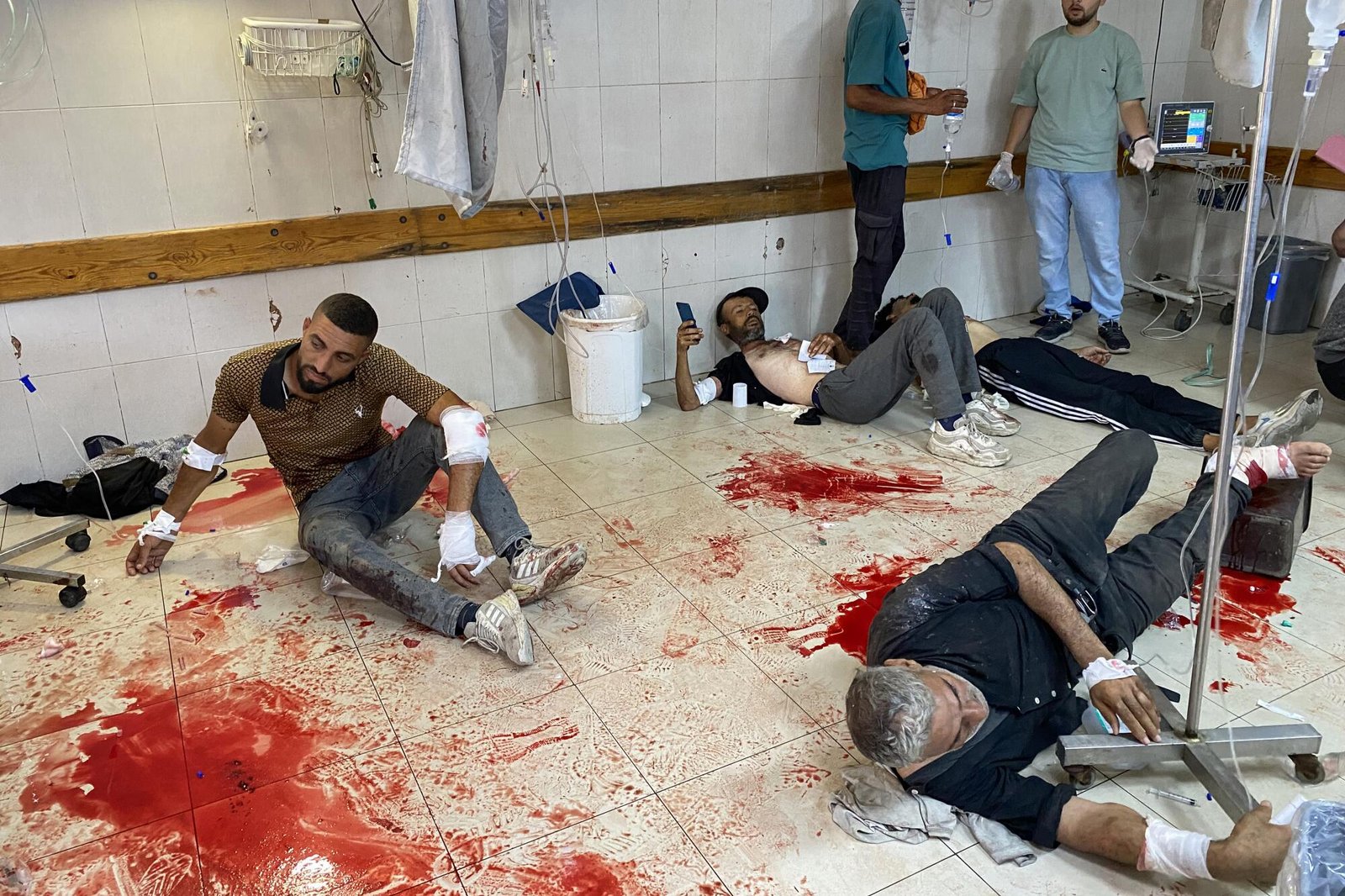 People lying on a blood-covered floor waiting to receive care