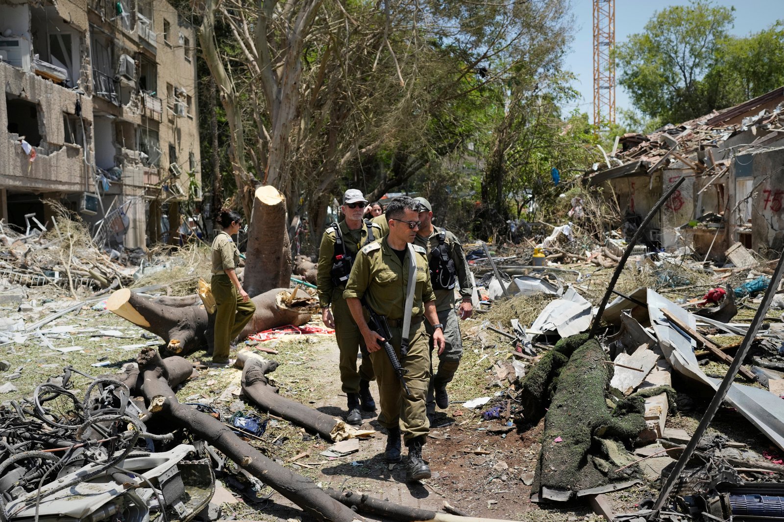 Israeli soldiers inspect a site in Tel Aviv struck by a missile launched from Iran, as attacks continue