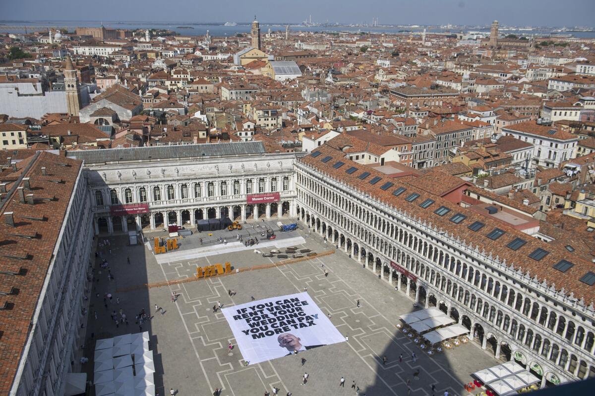 An aerial shot of large banner addressing Jeff Bezos and taxes laid out in Venice's St. Mark Square