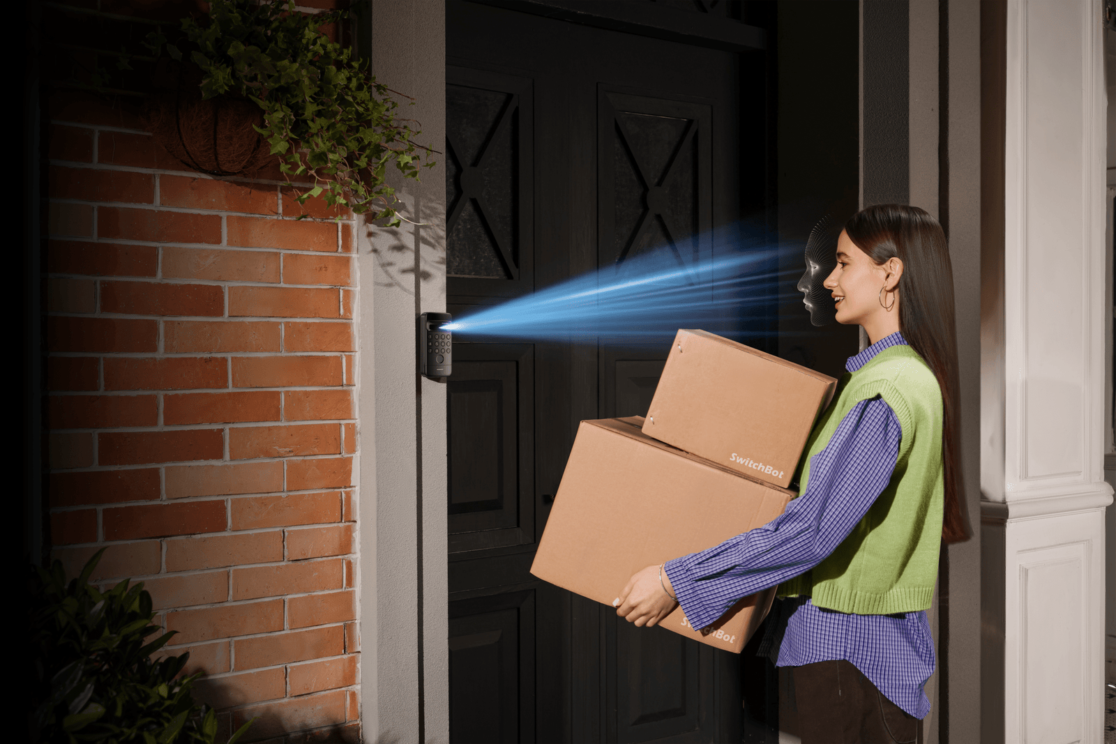 A woman holding packages approaches a front door where a keypad is scanning her face.