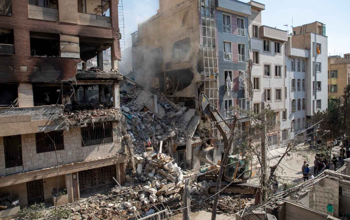 An excavator removes debris from a residential building that was destroyed in an attack by Israel in Tehran, on June 13, 2025.