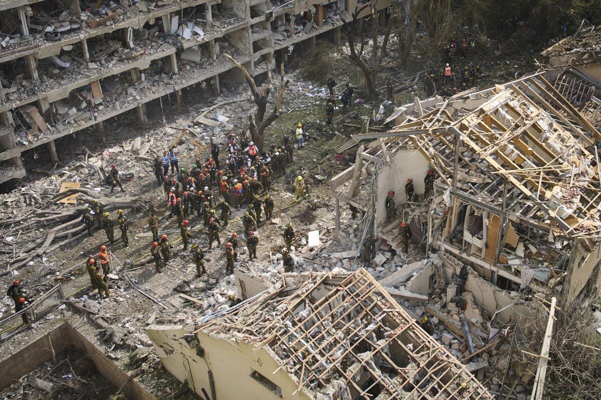 People stand amid a scene of destroyed buildings