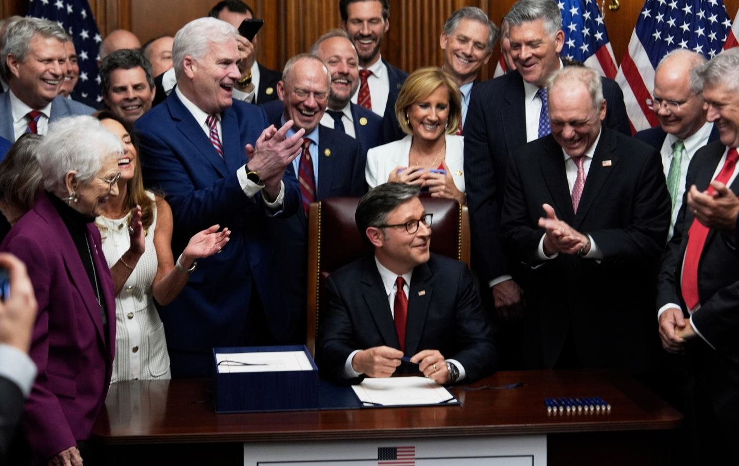 Speaker of the House Mike Johnson, R-La., surrounded by Republican members of Congress, signs President Donald Trump's signature bill of tax breaks and spending cuts, Thursday, July 3, 2025, at the Capitol in Washington.