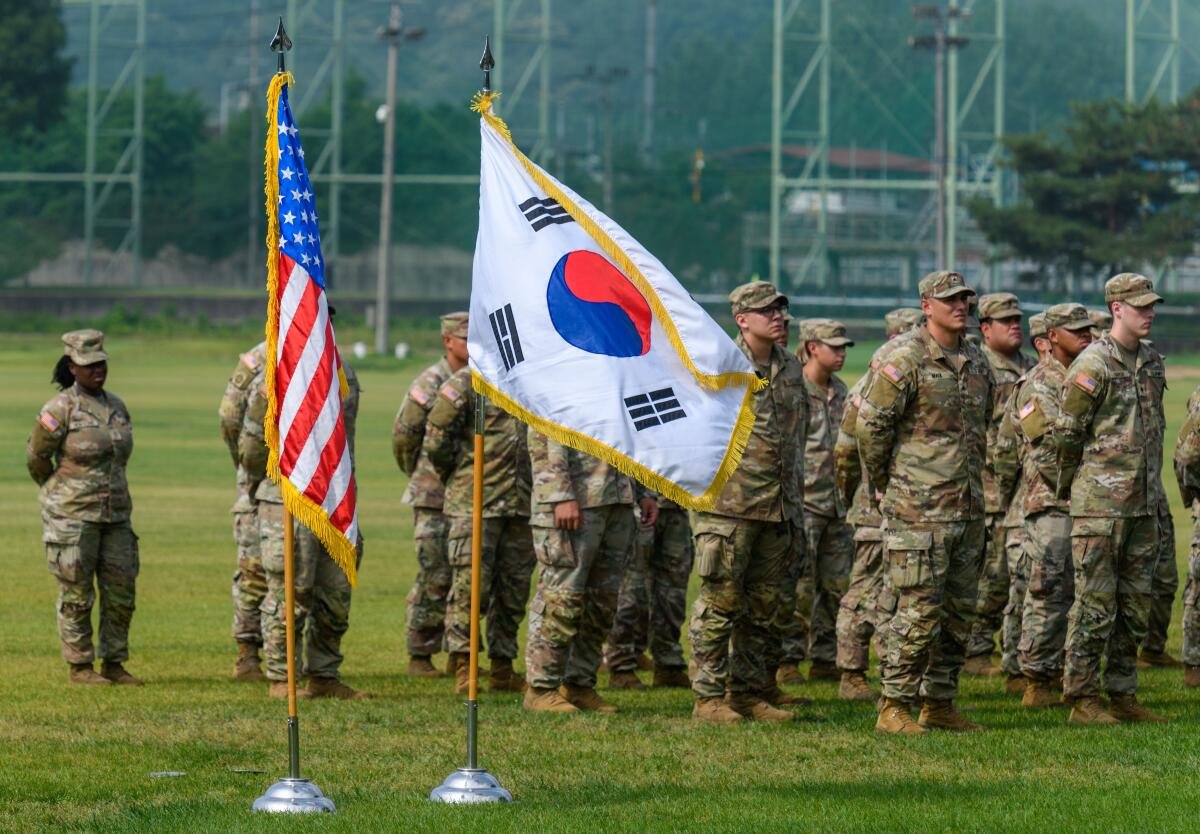 U.S. Army soldiers standing in a field with an American flag beside a South Korean flag
