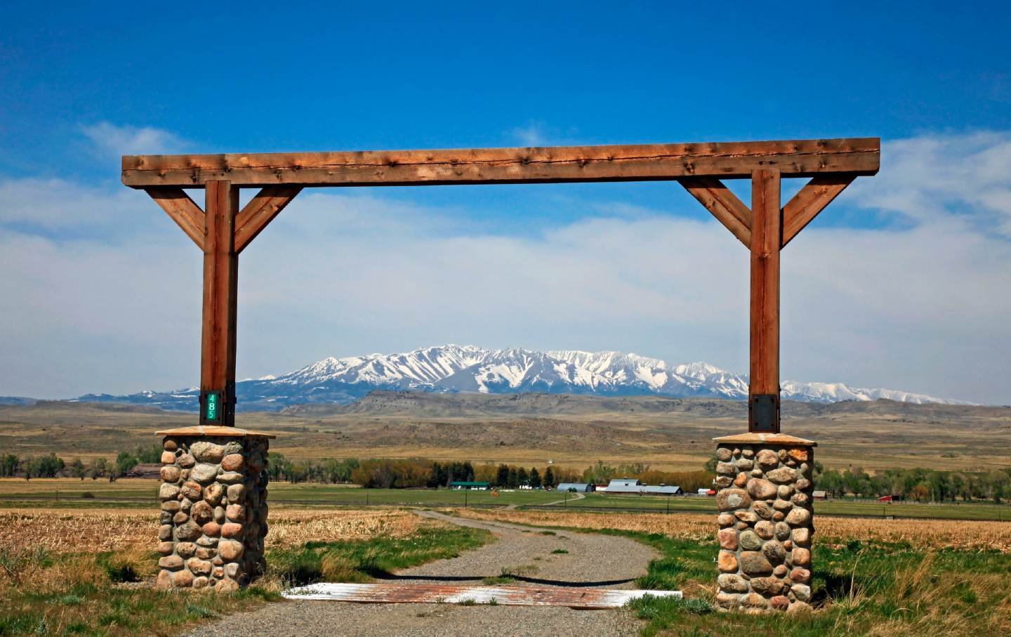 View through Montana ranch entrance to rangeland with a view of central Montana shows snow covered Crazy Mountains in the background. The Crazy Mountains rise to over 11,000 feet and are located north of Interstate-90 between Billings and Bozeman Montana; they can be seen for many miles along this stretch of Interstate.