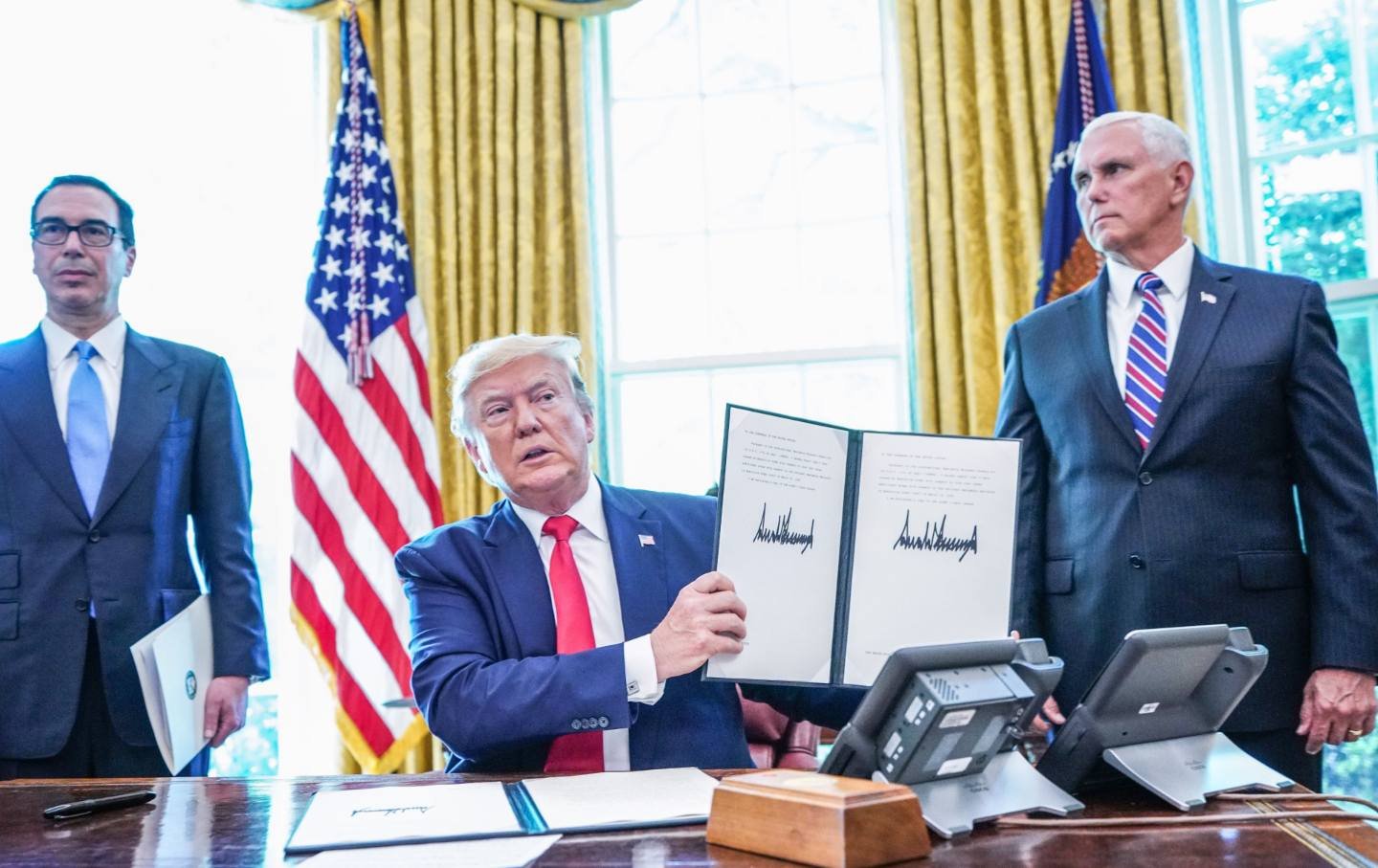 Donald Trump signs with US Vice President Mike Pence(R) and US Secretary of Treasury Steven Mnuchin at the White House on June 24, 2019, “hard-hitting sanctions” on Iran’s supreme leader.