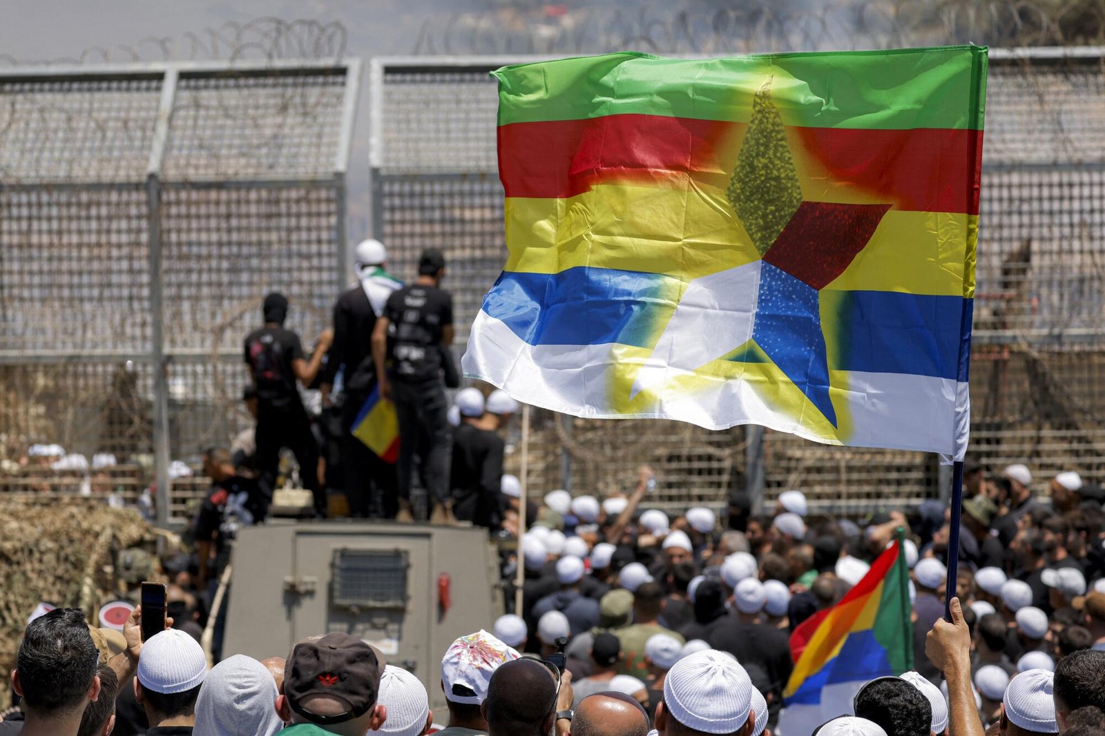 members of the Druze community demonstrate before Israeli forces by the barbed-wire fence