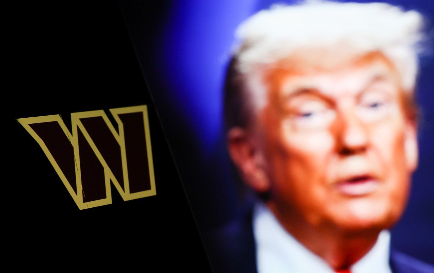 The Washington Commanders logo displayed on a phone screen next to a photo of Donald Trump