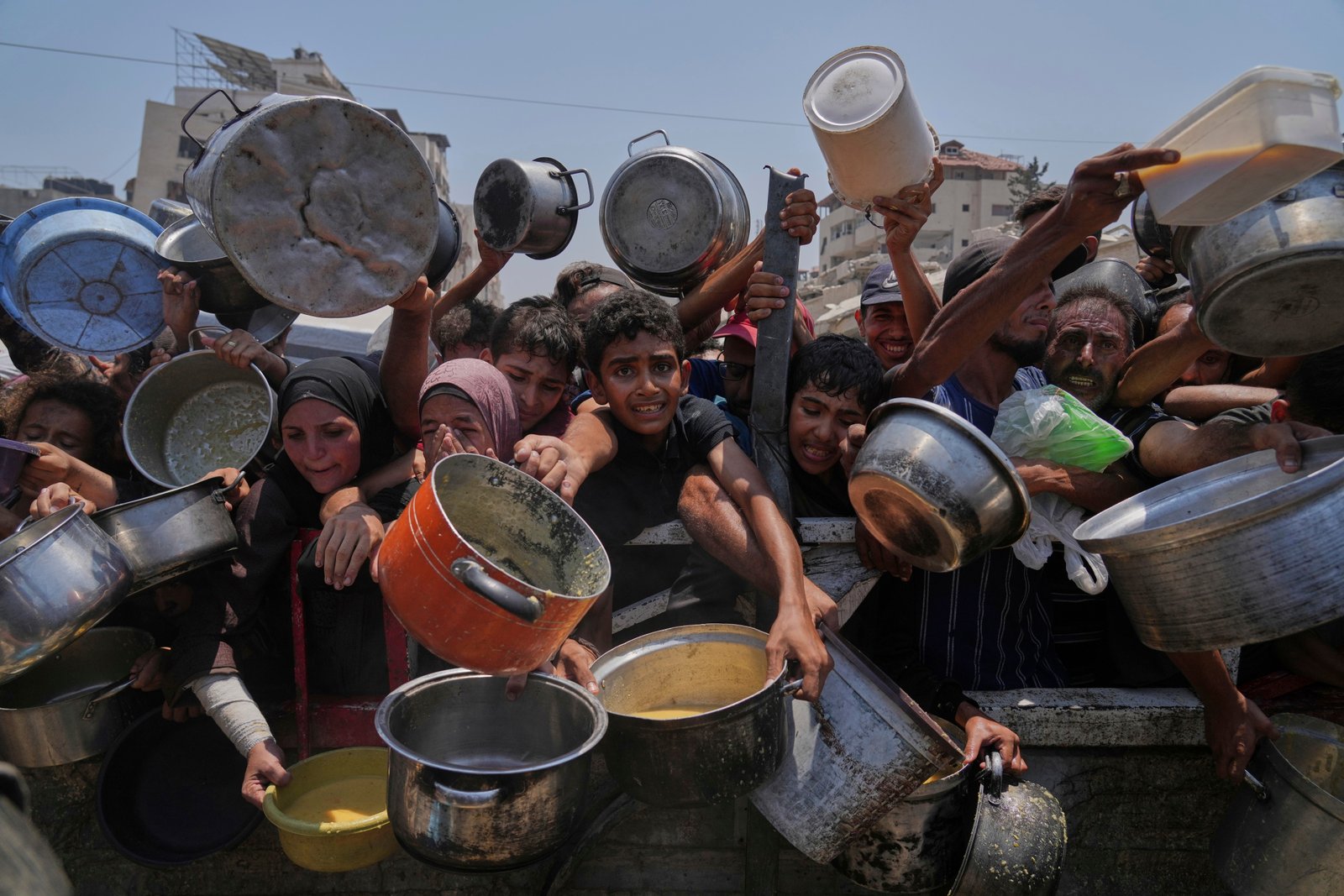 Palestinians struggle to get donated food at a community kitchen in Gaza City