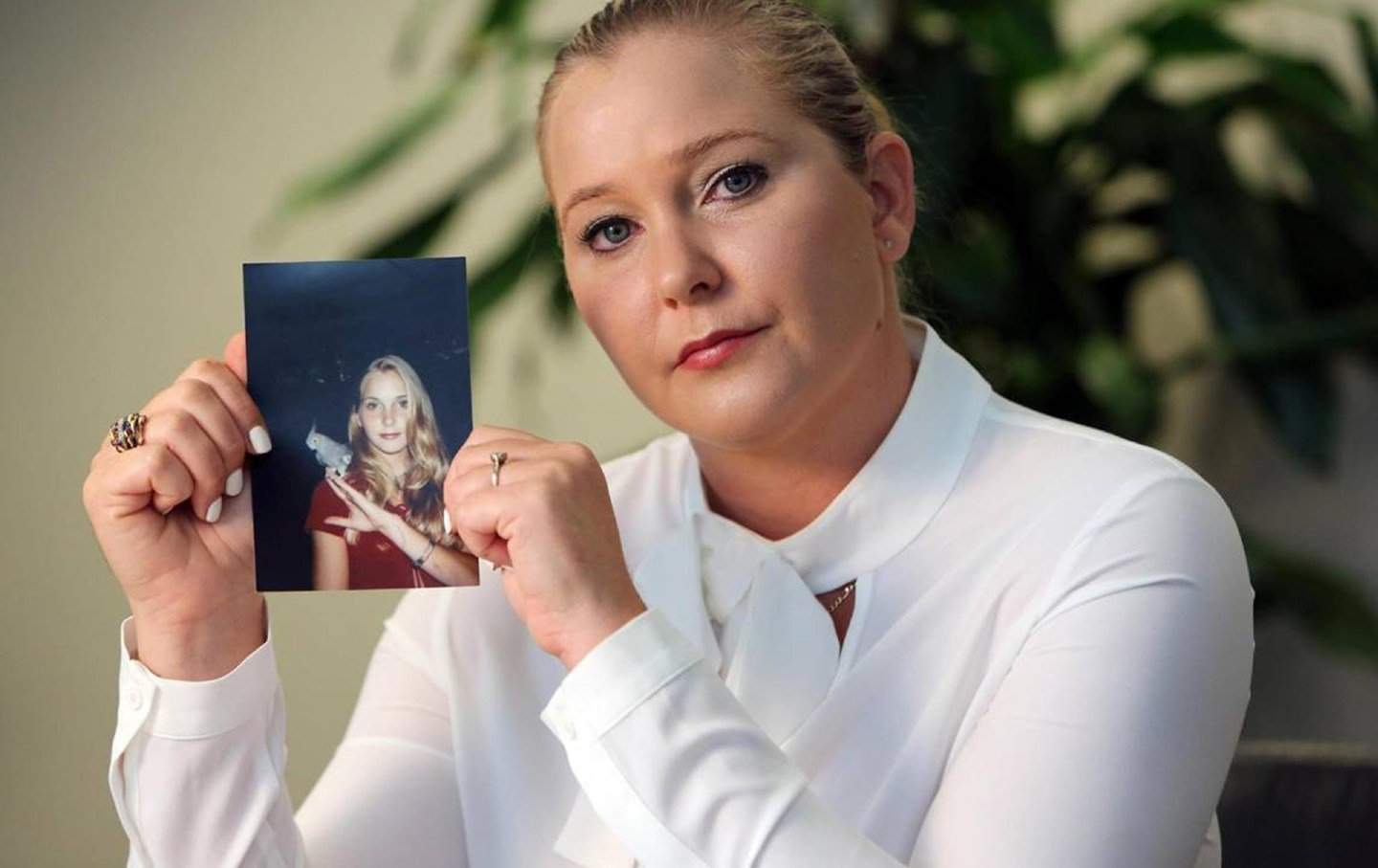 Virginia Roberts Giuffre holds up a photo of herself as a teen.