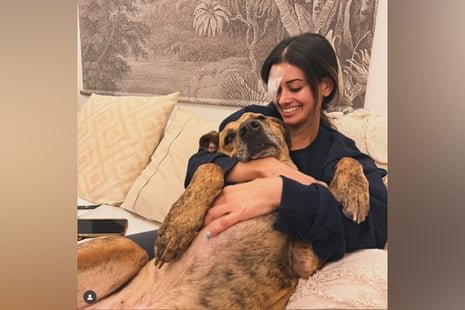 A woman with dark hair and a bandaged eye holds a dog.
