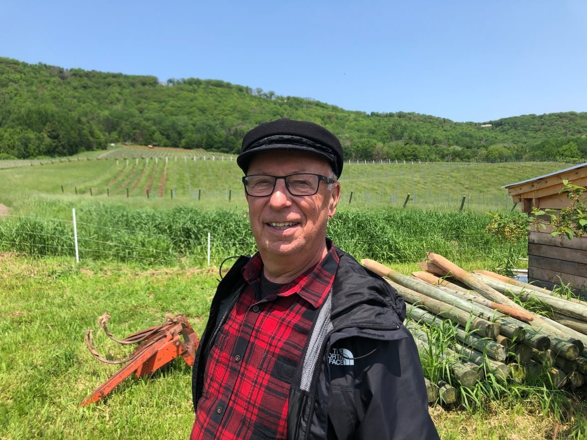 A man in a red shirt and black hat stands in a field