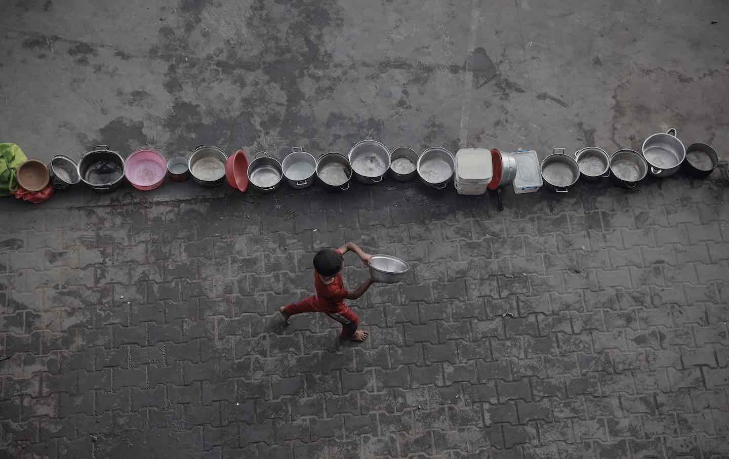 Palestinians, struggling with hunger, form a line to receive hot meals in Gaza's al-Zeitoun neighborhood on July 31, 2025.