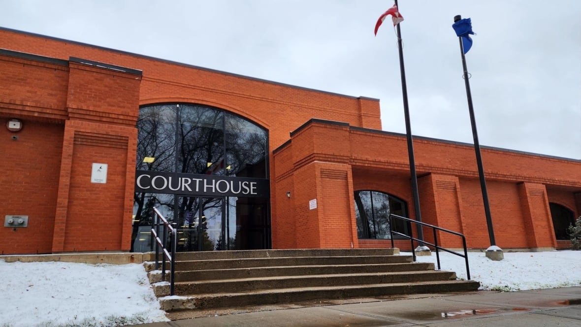 Reddish-orange building with stairs leading up to front entrance. A sign reads "Courthouse" above the entrance.