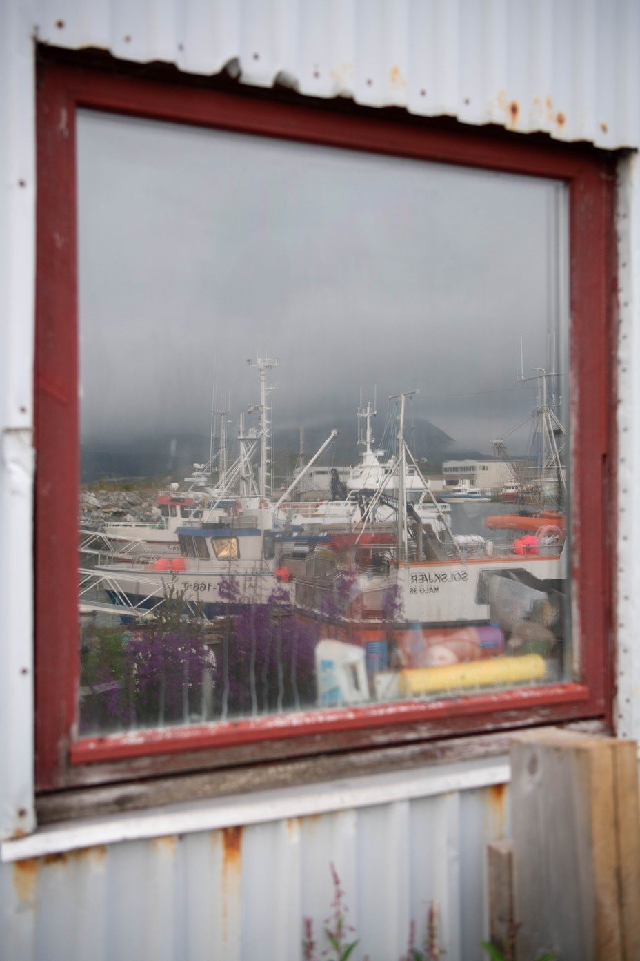 A color photograph of fishing boats reflected in a window of a building